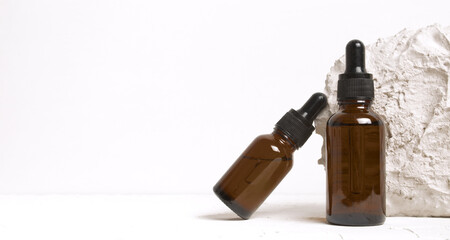 Serum glass bottle with pipette near brick stone on white background. Natural Organic Spa Cosmetic concept. Front view. Place for your text.