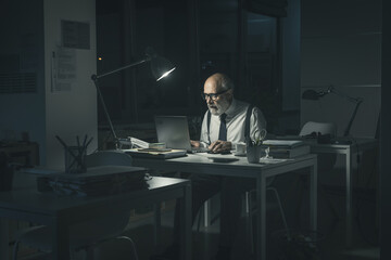 Stressed businessman working with his laptop late at night