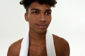 Fototapeta na wymiar Black curly sportsman with towel looking away