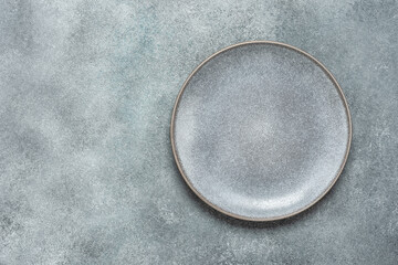 Empty gray plate on gray rustic concrete background. Top view, flat lay.