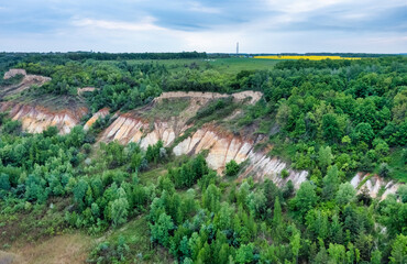 Fototapeta na wymiar Colorful clay hills overgrown with green trees. Natural abstract landscape, aerial view from drone
