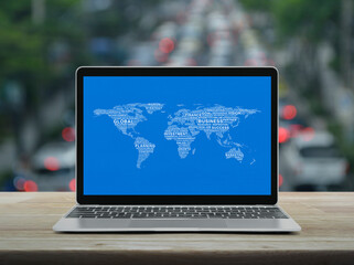 Global business words world map with modern laptop computer on wooden table over blur of rush hour with cars and road in city, Global business online concept, Elements of this image furnished by NASA