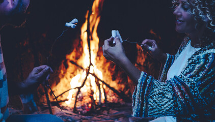 Happy couple eat marshmallows near a cozy fireplace flame at home in cozy home - festive...