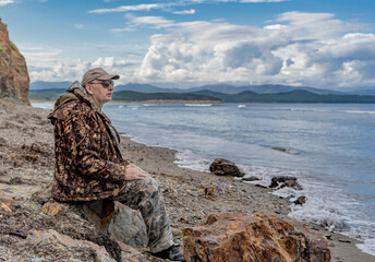 Portrait of a pensive elderly man on the seashore looking at the sea against the backdrop of rocks thinking about the meaning of life.imagination and vision of a happy future.
