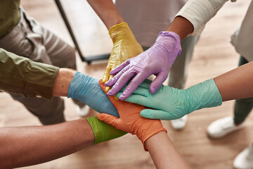 Team in medical gloves stack hands on each other