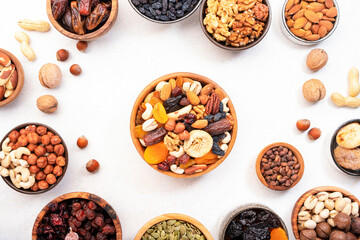 Dried fruits nuts in bowls set. Dry apricots, figs, raisins, walnuts, almonds and other. Healthy nutritious snacks. White table background, top view, copy space