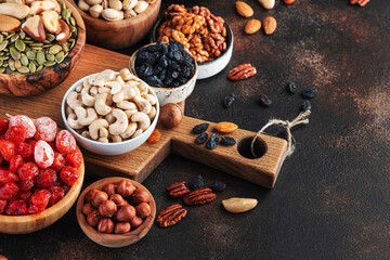 Dried fruits nuts in bowls set. Dry apricots, figs, raisins, walnuts, almonds and other. Healthy nutritious snacks. Brown table background, copy space
