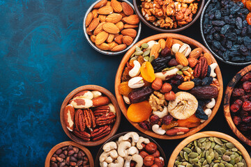 Nuts and dried fruits in assortment. Dry apricots, figs, raisins, walnuts, almonds and other. Blue table background, top view, copy space