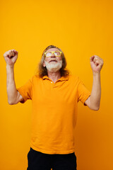 Senior grey-haired man yellow t-shirt and glasses posing yellow background