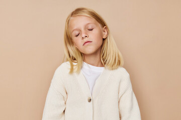 Positive little girl gestures with his hands on a beige background