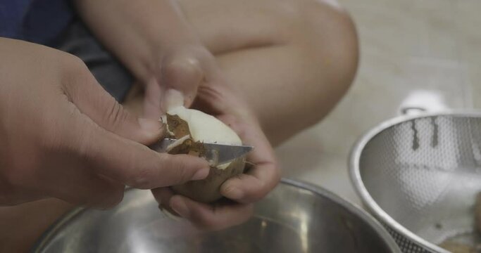 Asian female peeling dioscorea Pseudotomentosa in a domestic kitchen. Food preparation concept. 
