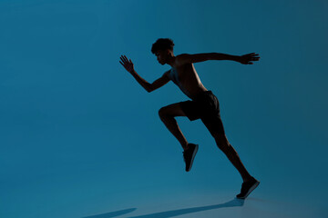 Fototapeta na wymiar Concentrated sports man running on blue background