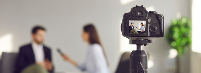 Blurry copy space banner background with a closeup shot of a modern video camera with a digital...