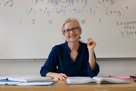 Portrait of high school math teacher sitting at desk working on assignments for students.