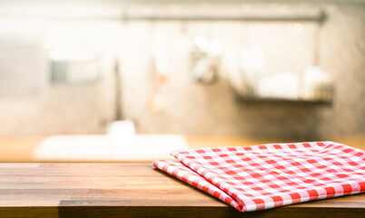 Red fabric,cloth on wood table top on blur kitchen counter (room)background.