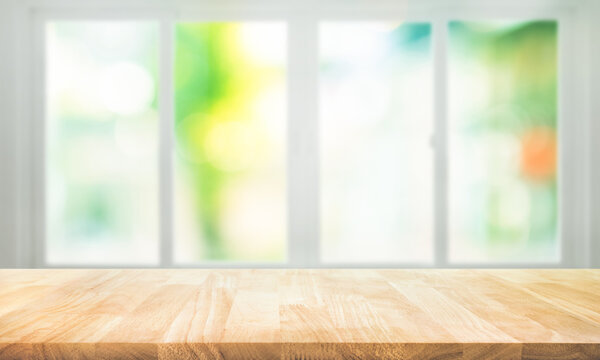 Empty wood table top on blur abstract green garden from window view.