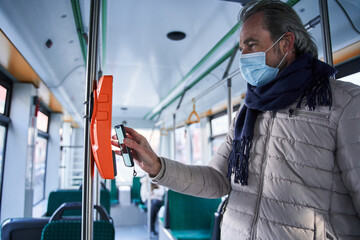 Senior caucasian man in protective medical mask in public transport bus