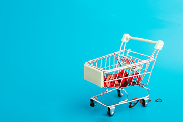 Valentine's Day-romance, love, lots of hearts in a shopping cart trolley from the supermarket on a blue background with copy space