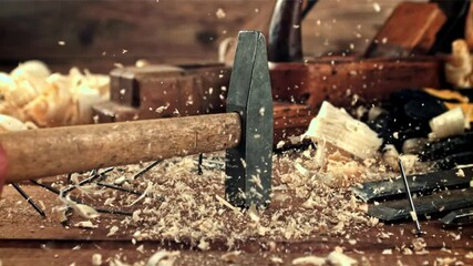 A hammer falls on a table with sawdust and nails. On a wooden background.Filmed is slow motion 1000 frames per second. High quality FullHD footage - Powered by Adobe