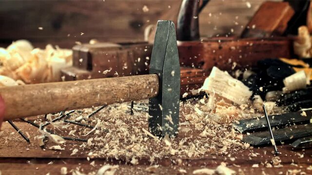 A hammer falls on a table with sawdust and nails. On a wooden background.Filmed is slow motion 1000 frames per second. High quality FullHD footage