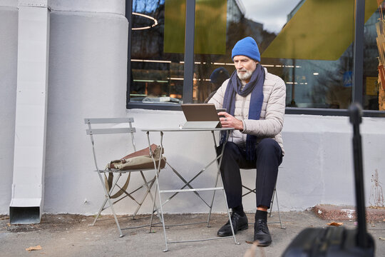 Mature male using tablet computer while spending time at the cafe at the street
