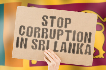 The phrase " Stop Corruption in Sri Lanka " on a banner in men's hand with blurred Sri Lankan flag on the background. Forbidden. Prevent. Wealth. Offence. Corruptness. Economy. Corruptible. Political