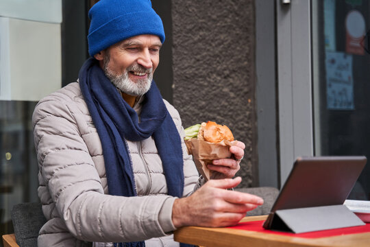 Overjoyed old man having video call by the internet connection at his tablet