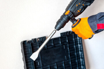 Hands in protective gloves, hammer drill, perforator, case, tool box