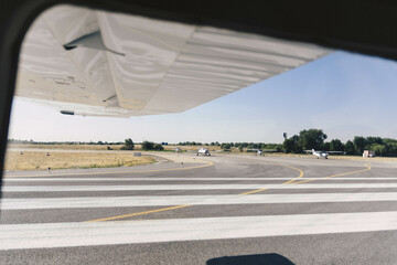 Side view of the wing of a small plane on the runway with other planes waiting to take off. Madrid Airport - Cuatro Vientos