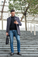young entrepreneur walking in the city, businessman dressed casual using smart phone to work and stay connected, new business concept and trading on line, checking crypto currency app