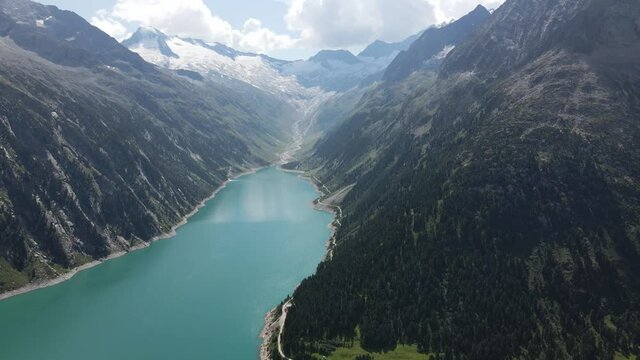 Paralax drone shot of a magical lake in the valley. Beautiful green lake in the valley of austrian alps. 