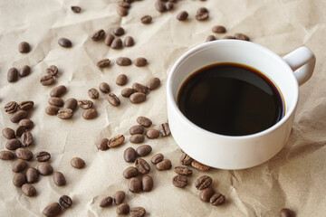 Coffee cup and coffee beans on crumple brown paper background