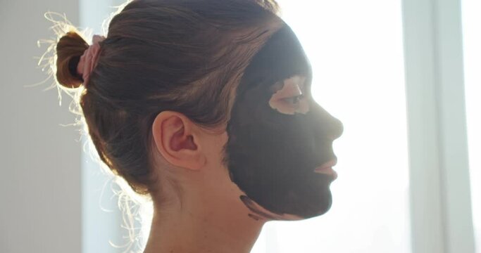 portrait of a woman at home in a black cosmetic mask
