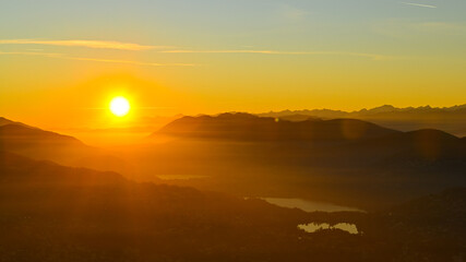 Fototapeta na wymiar Sole che tramonta sopra il lago, bellissimo momento nel mese di ottobre, con scia dorata sopra le montagne