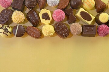 Chocolate cookies and pralines for a holiday event on a golden background with large copy space. Flat lay
