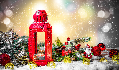 A lit red lantern amid Christmas decorations, standing in the falling snow on a Christmas lighted night.