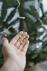 Golden glitter stars on a palm of a hand near christmas tree as festive background