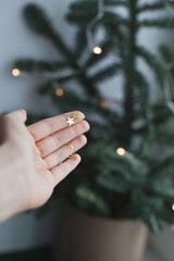 Golden glitter stars on a palm of a hand near christmas tree as festive background