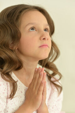 Portrait of cute girl praying in studio