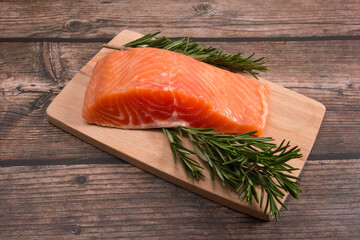 red salted fish on a cutting board with rosemary and lemon