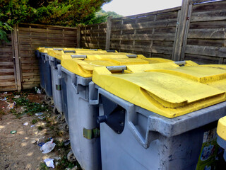 Compound of recycling bins with the ground littered in general waste.
