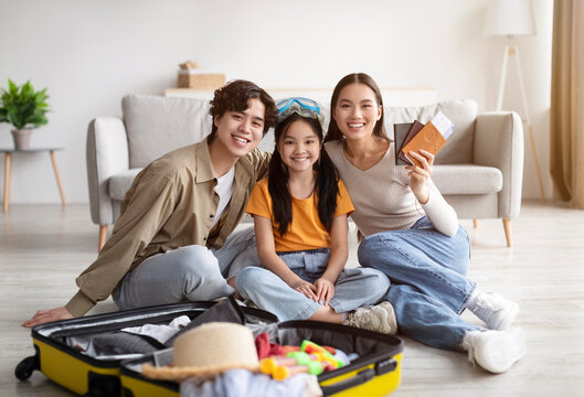 Cheerful Teenage Girl With Swim Glasses, Millennial Parents Collect Things In Suitcase For Vacation And Show Passport