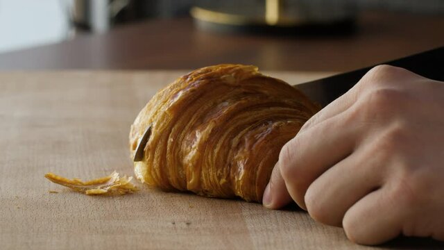 Close-up of cutting a fresh croissant in half