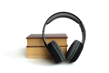 Black headphones with books lie on a white isolated background.