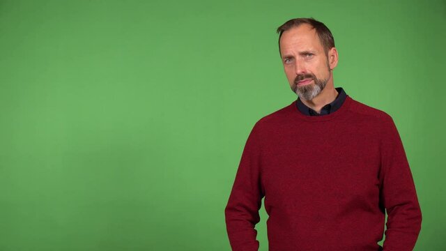 A middle-aged handsome Caucasian man looks seriously at the camera - green screen background