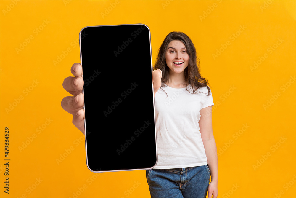 Poster cool mobile app. woman showing cellphone with big blank screen, demonstrating space for your website
