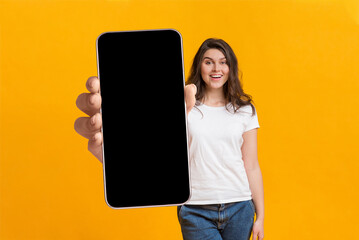 Cool mobile app. Woman showing cellphone with big blank screen, demonstrating space for your...