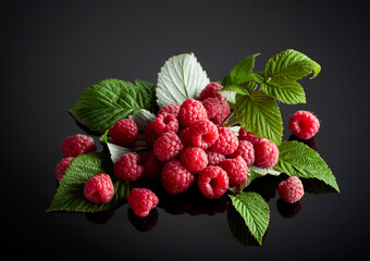Fresh raspberries with leaves on a black background.