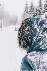 Close-up shot of a person from behind covered in snow in winter wonderland. 