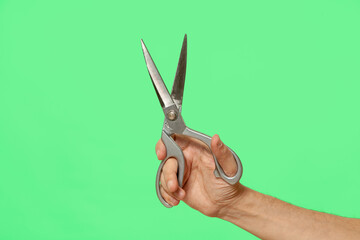 Scissors in hand isolated on green screen background.